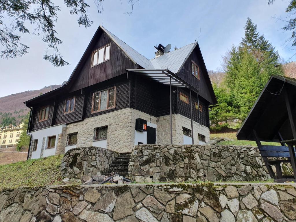 ein schwarzweißes Haus mit einer Steinmauer in der Unterkunft Chata Veronika in Terchová