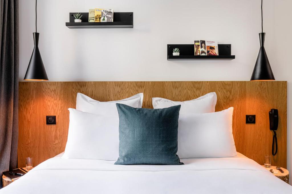 パリにある9Hotel Bastille-Lyonのベッドルーム1室(白いシーツと青い枕のベッド1台付)