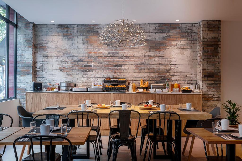 a restaurant with wooden tables and chairs and a brick wall at 9Hotel Bastille-Lyon in Paris