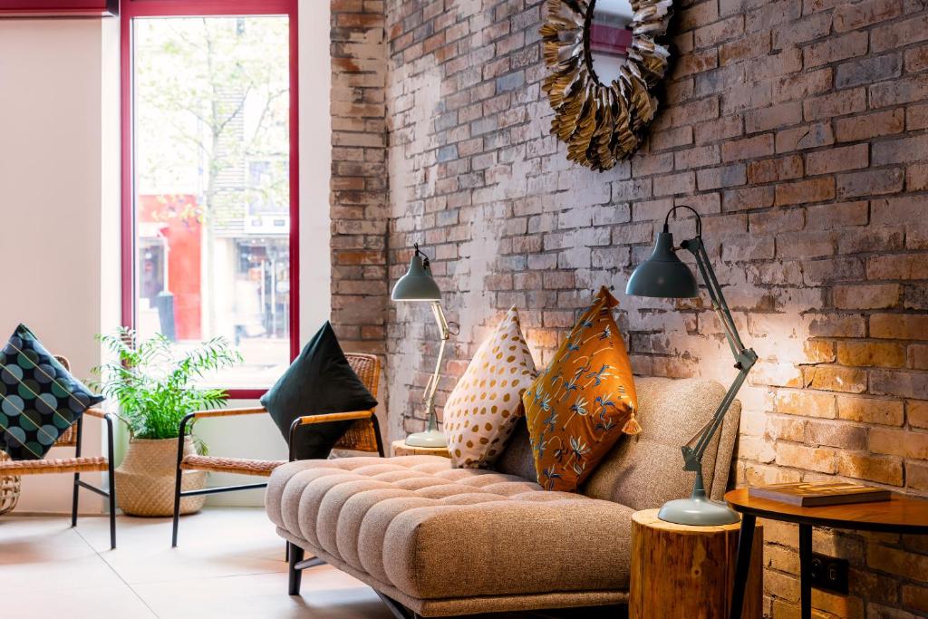 a living room with a couch and a brick wall at 9Hotel Bastille-Lyon in Paris