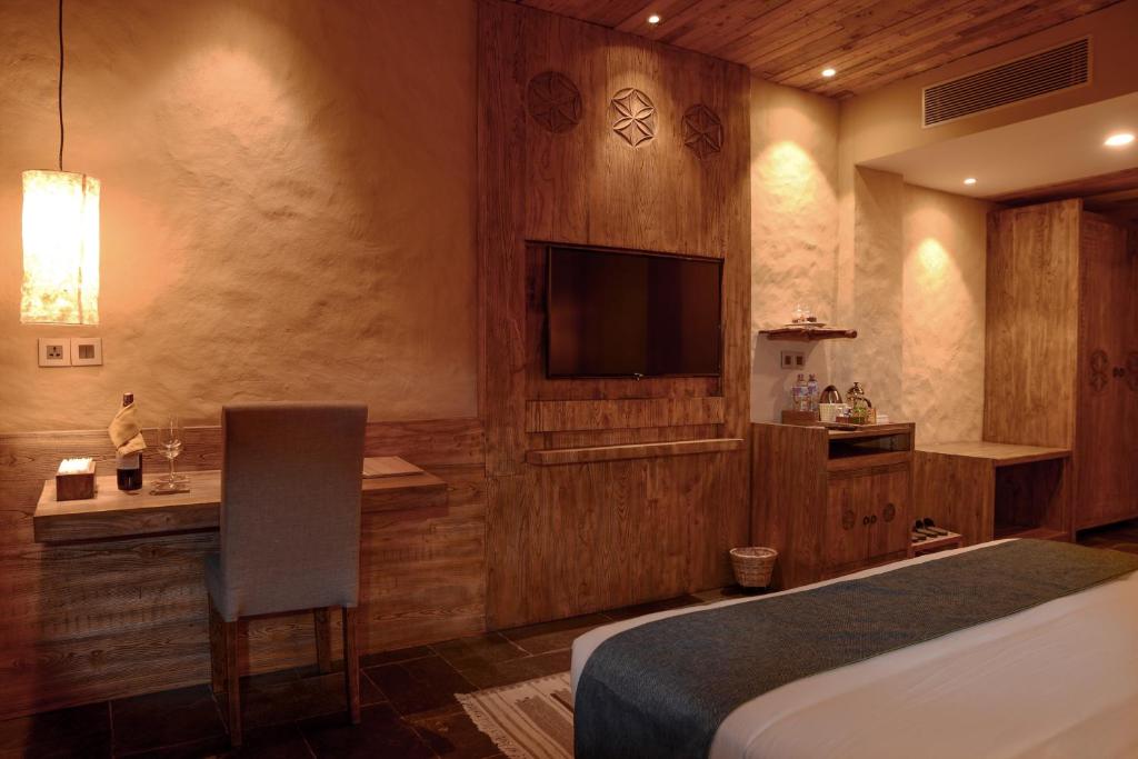 a bedroom with a bed and a desk and a television at Sarangkot Mountain Lodge in Pokhara