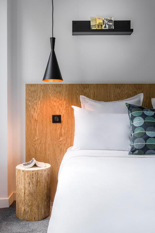 a bedroom with a white bed and a wooden headboard at 9Hotel Bastille-Lyon in Paris