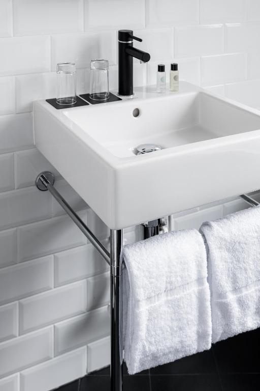 a white sink in a bathroom with towels at 9Hotel Bastille-Lyon in Paris