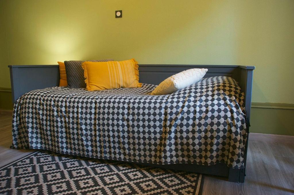 a bed with a checkered blanket and pillows on it at Le 110, un grand studio 2 étoiles, pour tout faire à pied in Aix-les-Bains