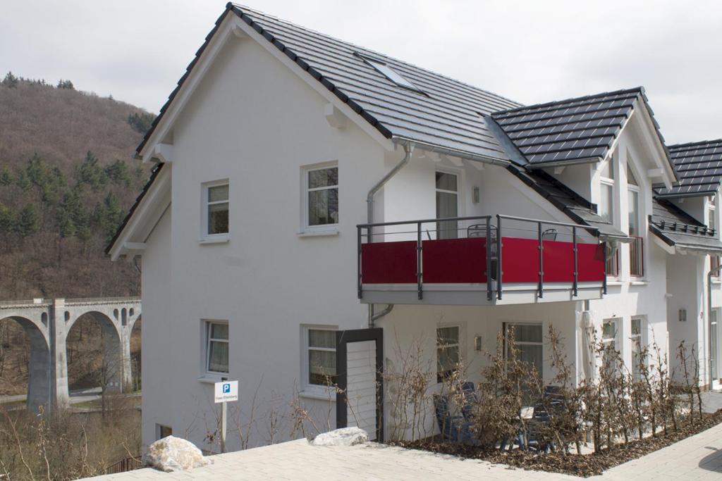 Una casa blanca con un balcón rojo. en Haus Am Lagunenbad Ferienwohnung Ettelsberg, en Willingen