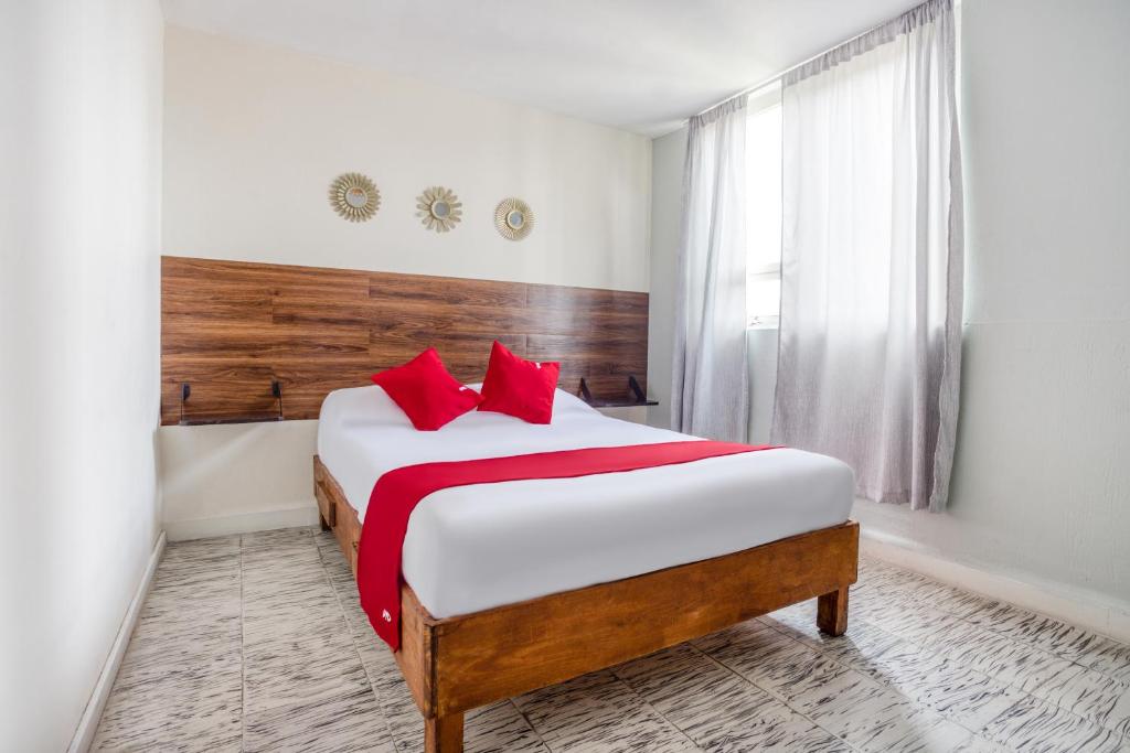 a bedroom with a large bed with red pillows at Hotel Suites Puebla in Puebla