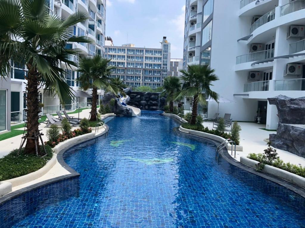 a swimming pool in the middle of a building with palm trees at Luxury Business Suits in Grand Avenue by Pattaya City Estates in Pattaya Central