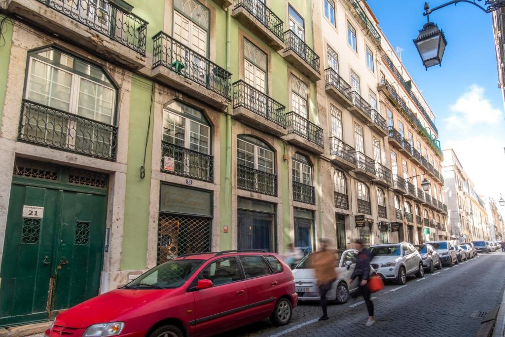 LV Premier Baixa DO في لشبونة: سيارة حمراء متوقفة في شارع مجاور لمبنى