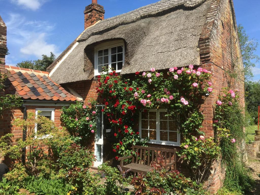 a thatched cottage with roses on the window at Rose Cottage in Ludham