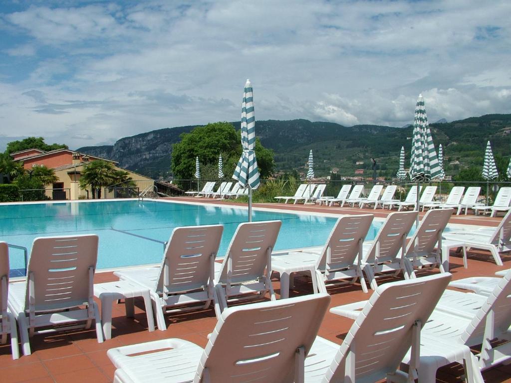 eine Reihe von Stühlen neben einem Pool in der Unterkunft Residence Corte Camaldoli in Garda
