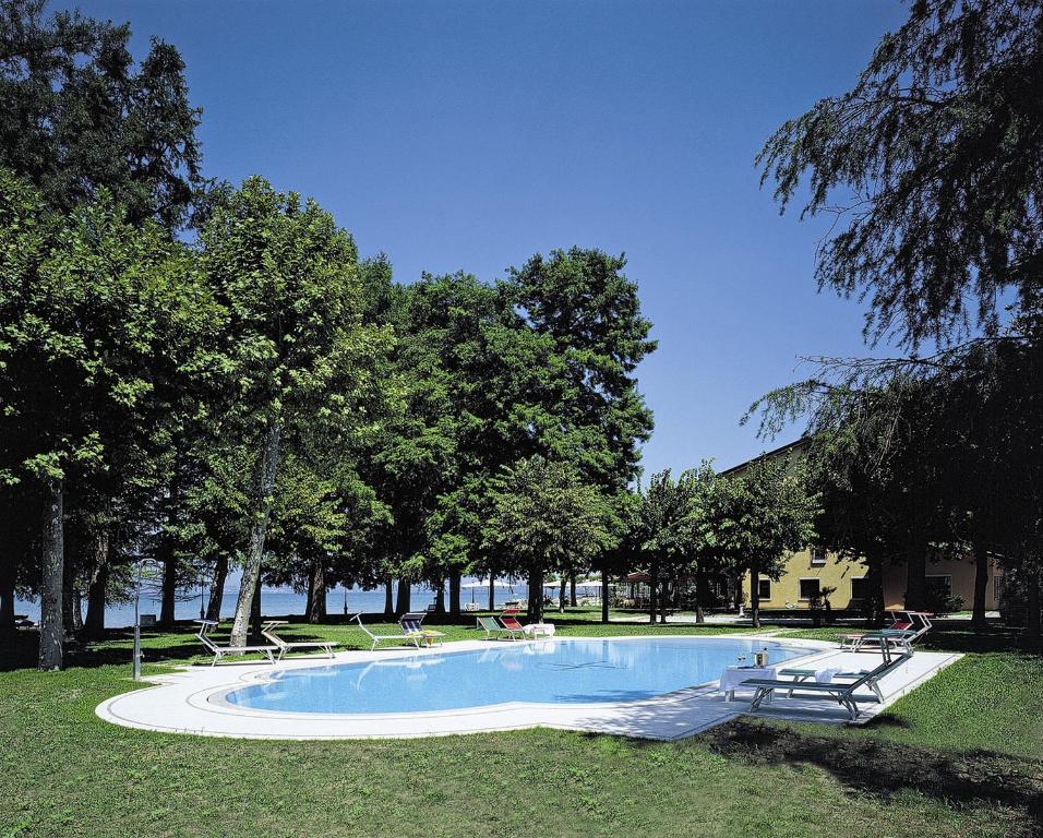 een zwembad in een park met bomen en stoelen bij Hotel Lugana Parco Al Lago in Sirmione