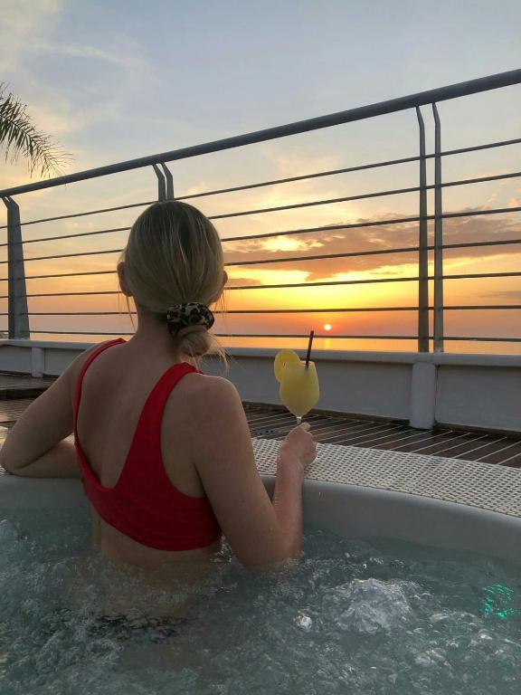 a woman sitting in a swimming pool with a drink at Residence Porto Ulisse in Parghelia