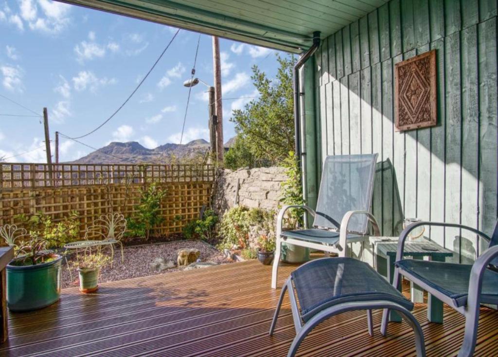 eine Terrasse mit 2 Stühlen und einer Bank auf einer Holzterrasse in der Unterkunft Hendre in Blaenau-Ffestiniog
