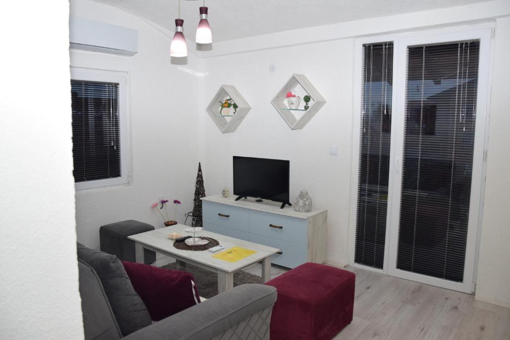 ein Wohnzimmer mit einem Sofa, einem TV und einem Tisch in der Unterkunft Markos Towers Apartments in Prilep