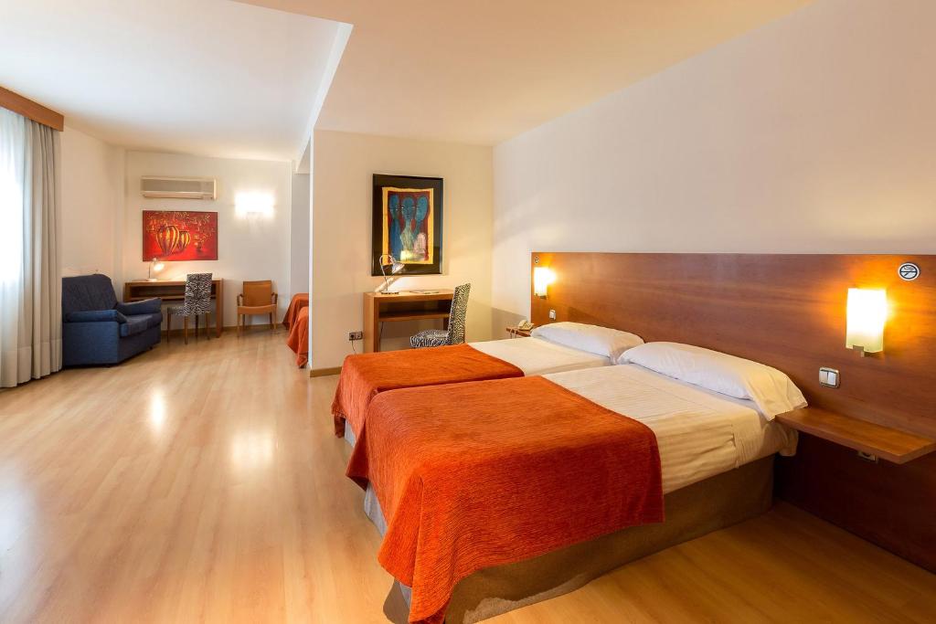 a bedroom with a large bed with an orange blanket at Hotel Torre Monreal in Tudela