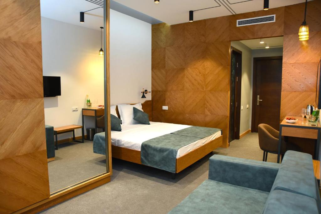 1 dormitorio con cama, escritorio y espejo en R&R Hotel en Ereván