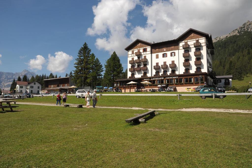 un gran edificio en un campo con gente parada frente a él en Hotel Lavaredo en Misurina