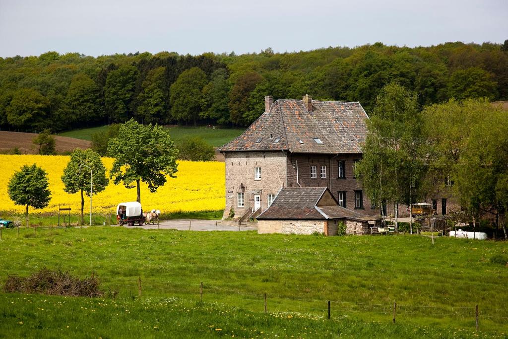an old house in the middle of a field of yellow flowers at B&B Einrade in Vaals