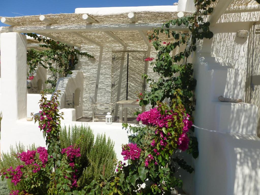a garden with pink flowers on a white wall at Portes Houses in Koufonisia