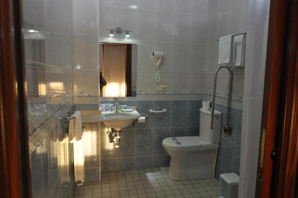 a bathroom with a toilet and a sink and a mirror at Pension Alameda in San Sebastián