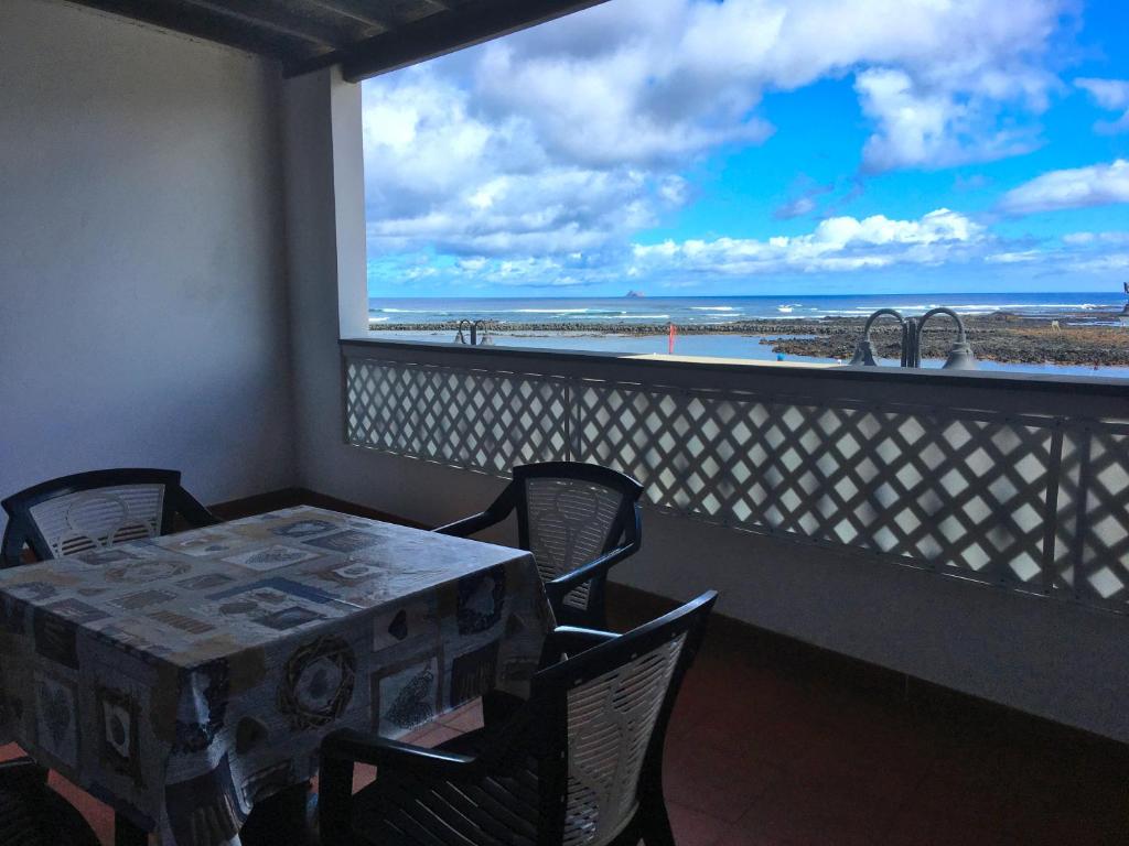 uma mesa e cadeiras numa varanda com vista para a praia em Orzola frente al mar em Orzola