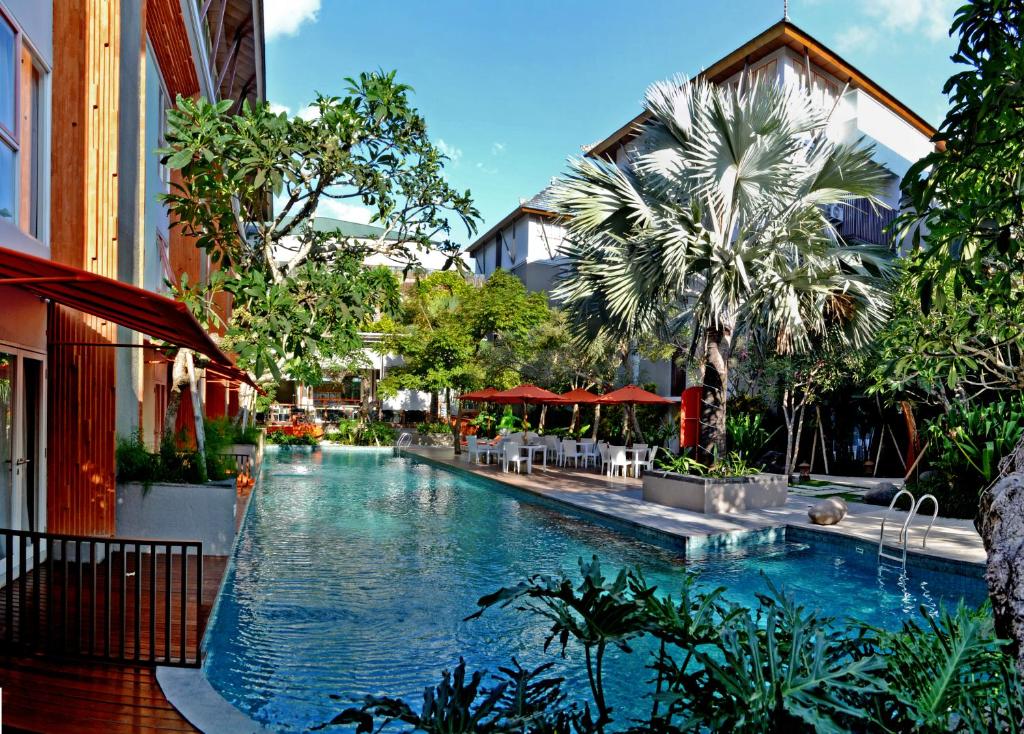 una piscina en un complejo con árboles y edificios en HARRIS Hotel & Residences Sunset Road, en Kuta