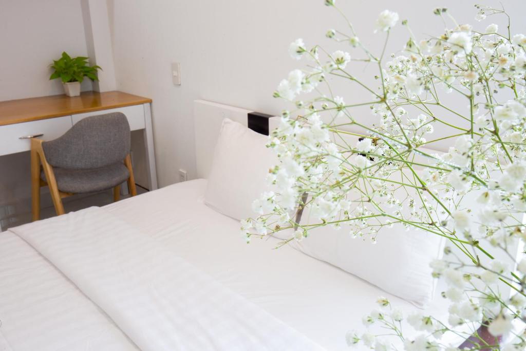 een slaapkamer met een bed met witte lakens en een plant bij HOSTIE SAIGON [WANDERLUST Home] in Ho Chi Minh-stad