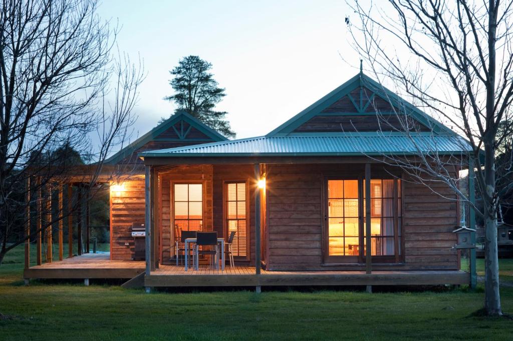 a small log cabin with a deck and windows at Beechworth Cedar Cottages in Beechworth