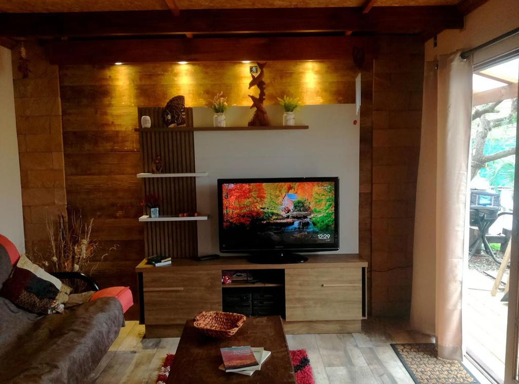 salon z telewizorem z płaskim ekranem na drewnianej ścianie w obiekcie Angeles w mieście La Paloma