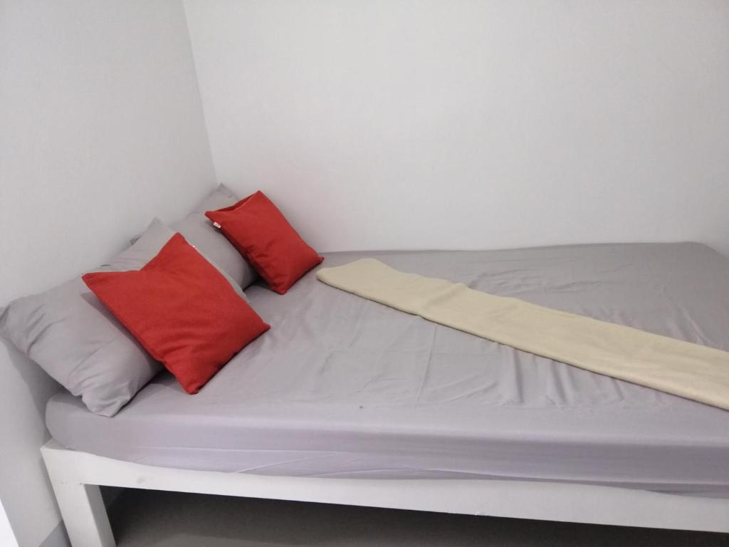 Katrina's Dorm في تارلاك: سرير صغير عليه وسادتين حمراء