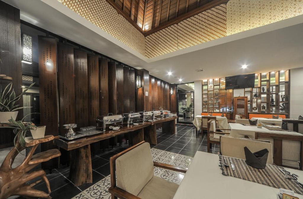a restaurant with wooden walls and tables and chairs at Gaing Mas Jimbaran Villas by Gaing Mas Group in Jimbaran