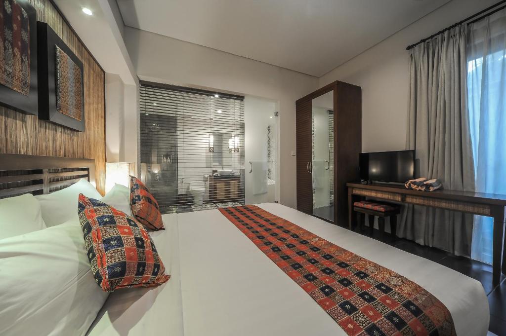 a hotel room with a large white bed and a television at Gaing Mas Jimbaran Villas by Gaing Mas Group in Jimbaran