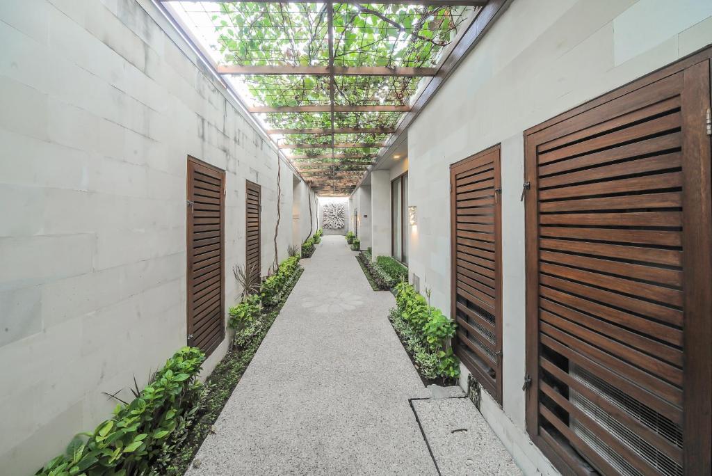 an alley with wooden doors and plants in a building at Gaing Mas Jimbaran Villas by Gaing Mas Group in Jimbaran