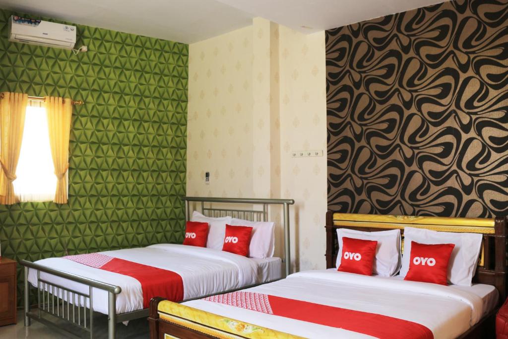 two beds in a room with green walls and red pillows at Super OYO 1722 Villa Ciparay Indah Syariah in Garut