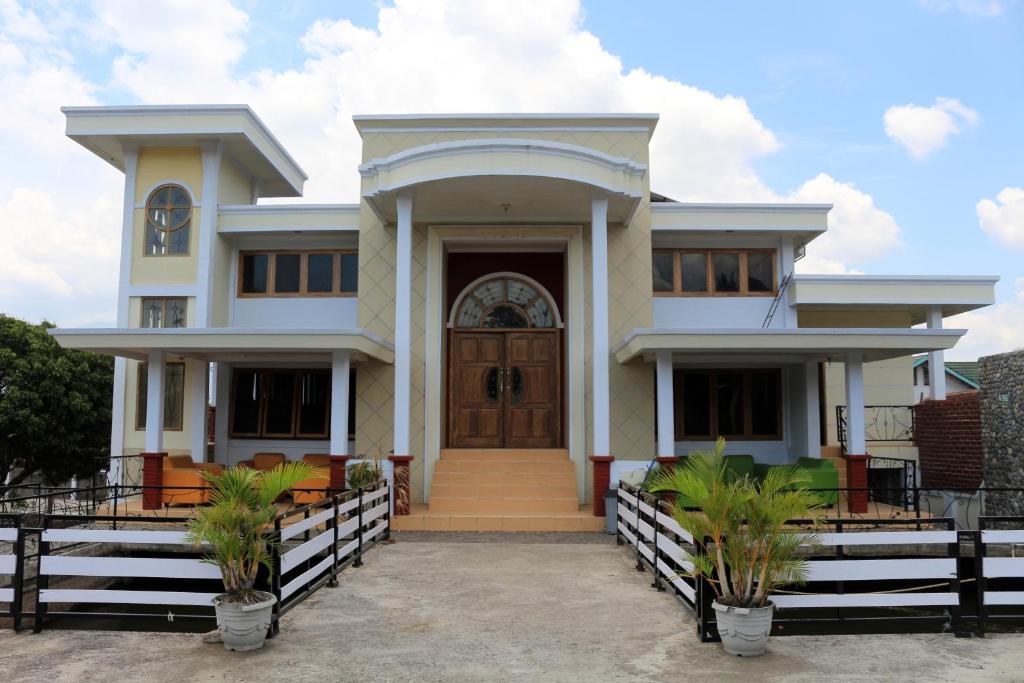 a white house with a wooden door at OYO 1722 Villa Ciparay Indah Syariah in Garut