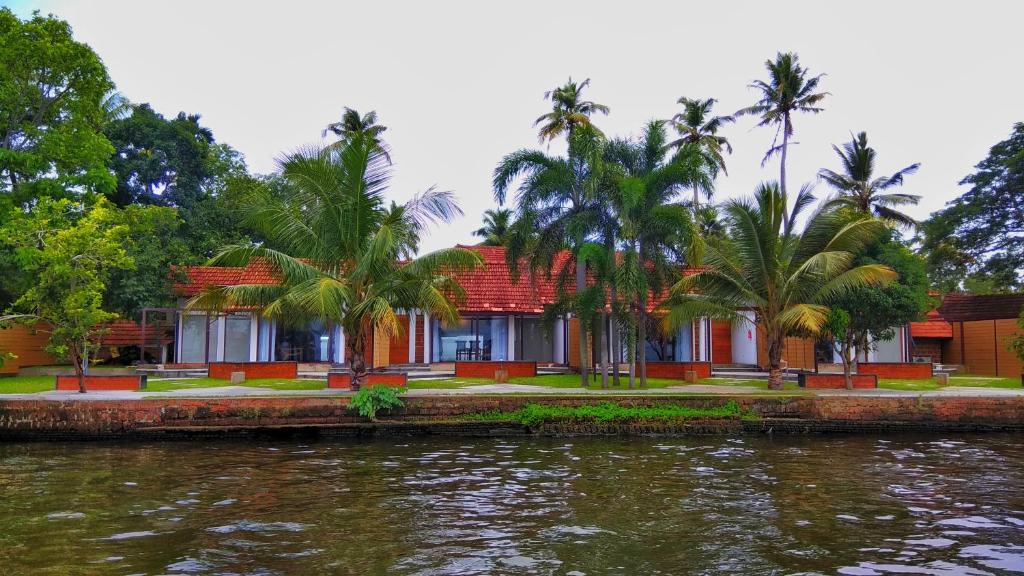 a house by the water with palm trees at Punnamada Resort in Alleppey