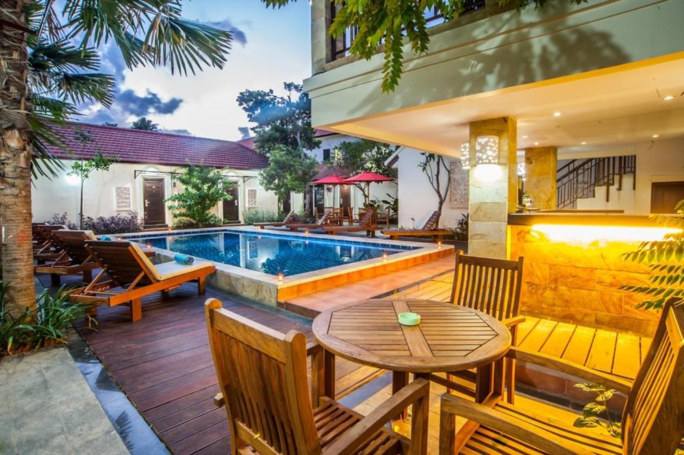 eine Terrasse mit Tisch und Stühlen und ein Swimmingpool in der Unterkunft KELAN-TEL BALI in Jimbaran