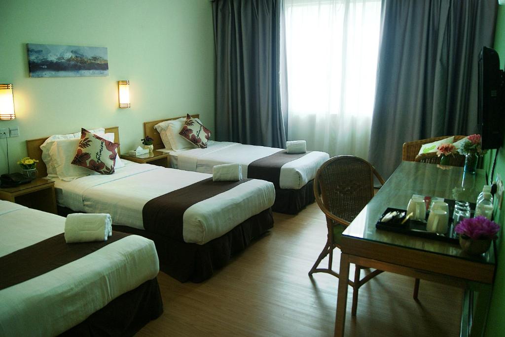 een hotelkamer met 2 bedden en een tafel bij Tang Dynasty Park Hotel in Kota Kinabalu