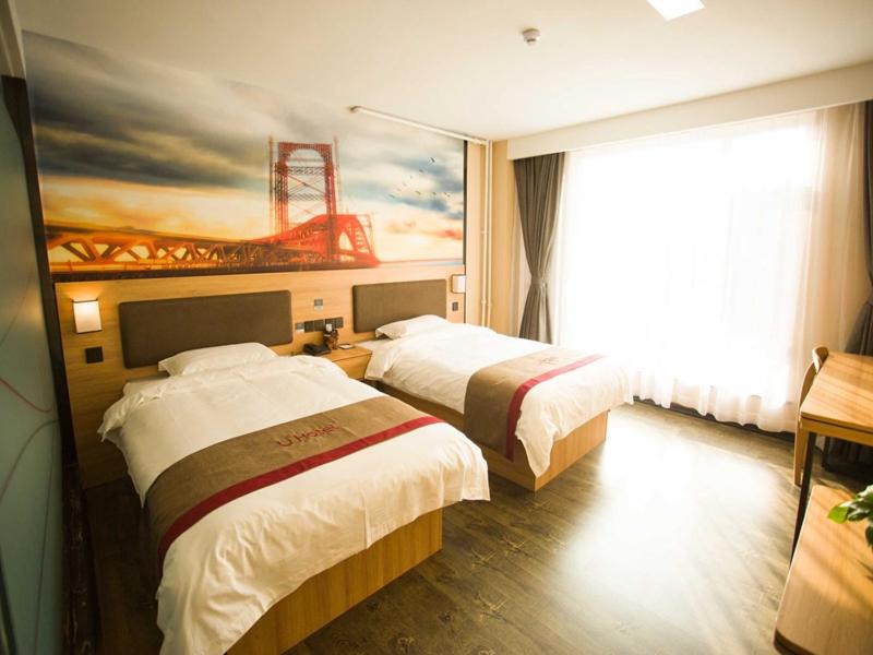 a hotel room with two beds and a painting on the wall at Thank Inn Plus Hotel Shandong Zibo Zhangdian District Jinjing Avenue Wanxianghui in Zibo