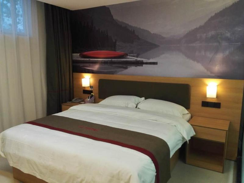 a bedroom with a large bed with a painting on the wall at Thank Inn Plus Hotel Shandong Heze Development Zone Huaihe Road in Heze
