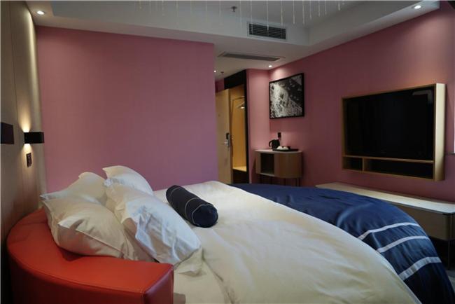 鹽城的住宿－兰欧江苏盐城大丰区永泰广场店，一间卧室设有一张大床和粉红色的墙壁