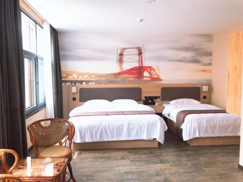 威海市にあるThank Inn Plus Hotel Shandong Weihai Rongcheng City Chengshan Avenue Rt-martのベッド2台が備わる客室で、壁には絵画が飾られています。