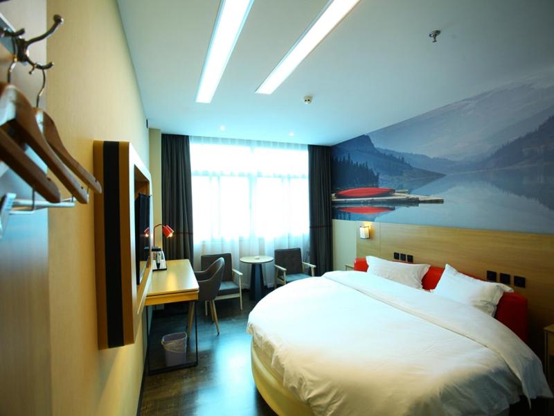 a hotel room with a bed and a desk and a room at Thank Inn Plus Hotel Yunnan Honghe Gejiu City Renmin Road in Gejiu