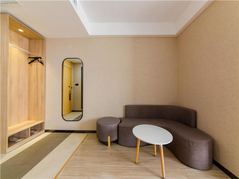 a room with a couch and a table and a mirror at Thank Inn Plus Hotel Hebei Shijiazhuang High-tech Zone Torch Plaza in Shijiazhuang