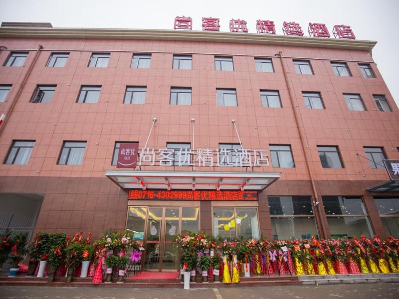 a building with a bunch of flowers in front of it at Thank Inn Plus Hotel Hubei Jingzhou City Jingzhou District Railway Station in Jingzhou