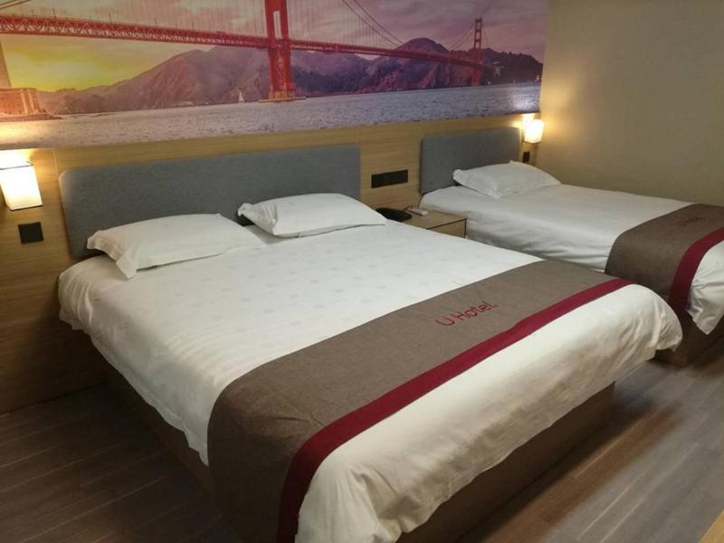 two beds in a hotel room with a painting on the wall at Thank Inn Plus Hotel Henan Shangqiu Suiyang District Shenhuo Avenue South in Shangqiu