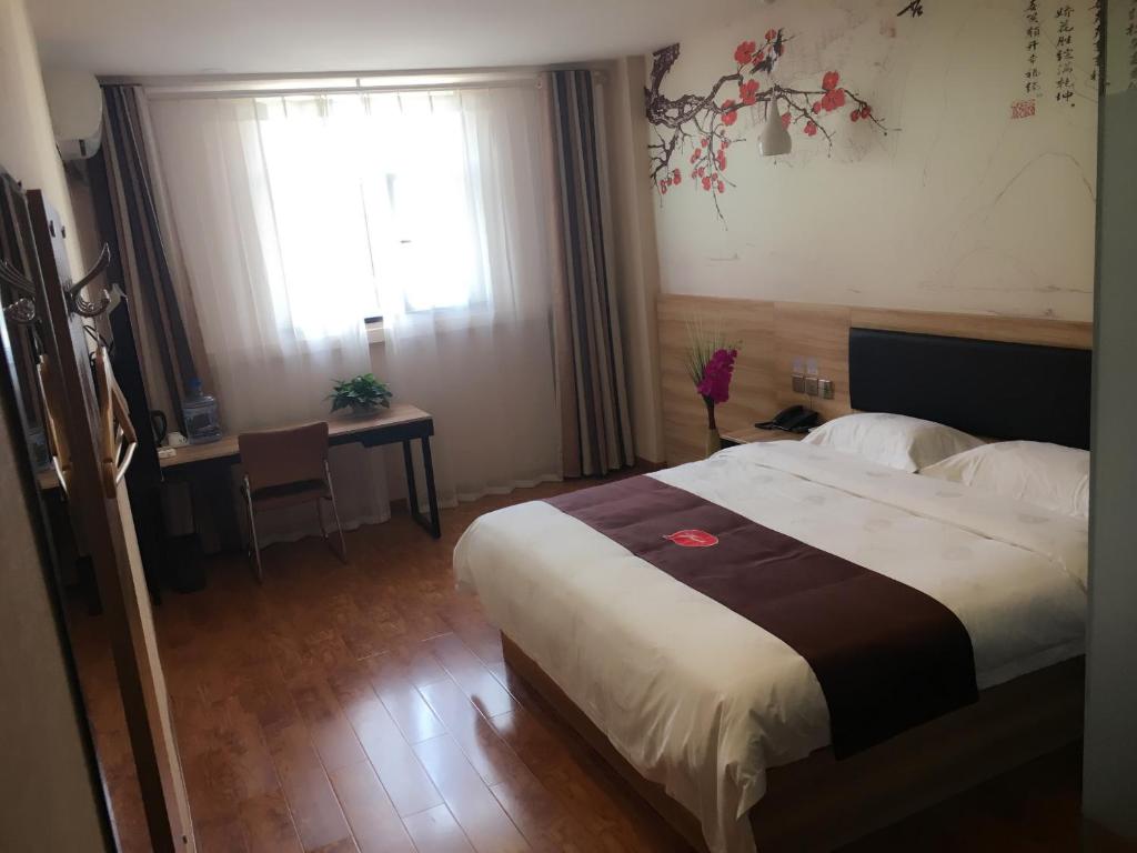 a bedroom with a bed and a table and a window at Thank Inn Plus Hotel Shandong Jining High-tech District Huangtun Plaza Commercial Building in Jining