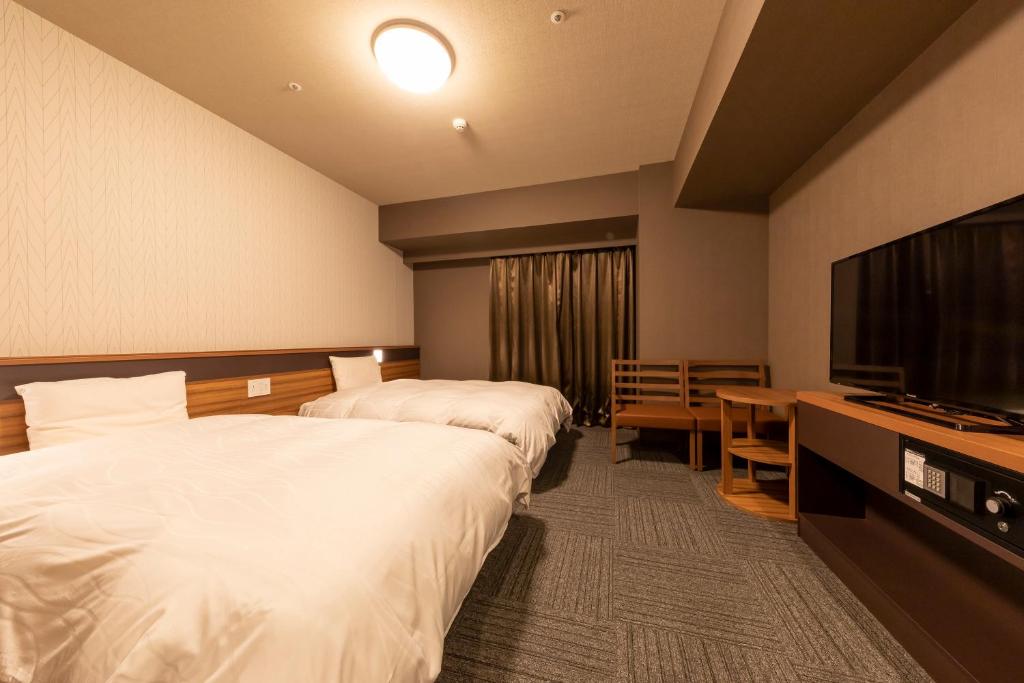 a hotel room with two beds and a flat screen tv at Dormy Inn Kawasaki Natural Hot Spring in Kawasaki