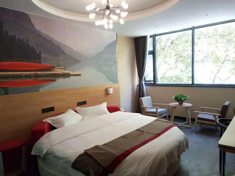 - une chambre avec un grand lit et une peinture murale dans l'établissement Thank Inn Plus Hotel Henan Sanmenxia Lingbao Changan Road, à Sanmenxia