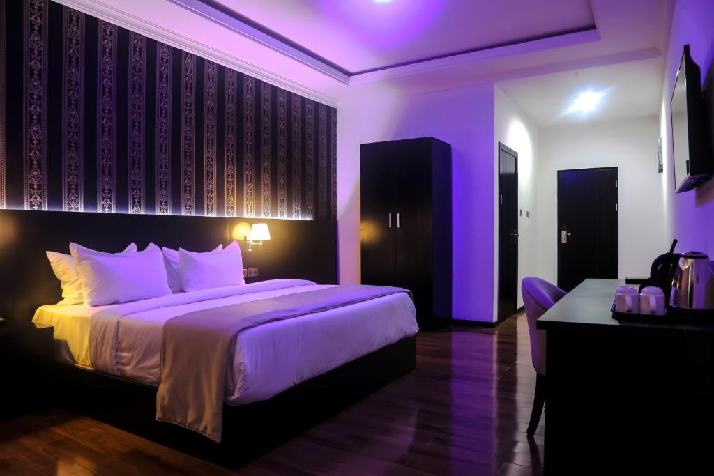 a purple bedroom with a large bed and a desk at BON Hotel Ikeja Residence in Ikeja